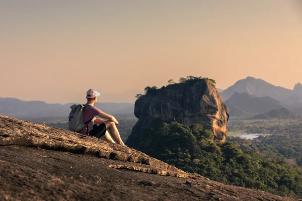 man-with-backpack-sitting-on-rock-and-looking-at-l-2024-07-22-17-48-01-utc